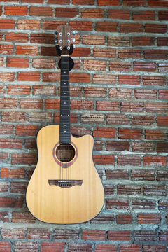 Acoustic guitar with brick wall background. © Jittima