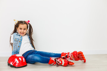 Happy little girl with roller skates and protective gear resting - isolated
