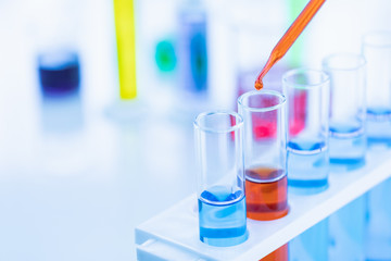 Someone dropping red liquid in test tubes..