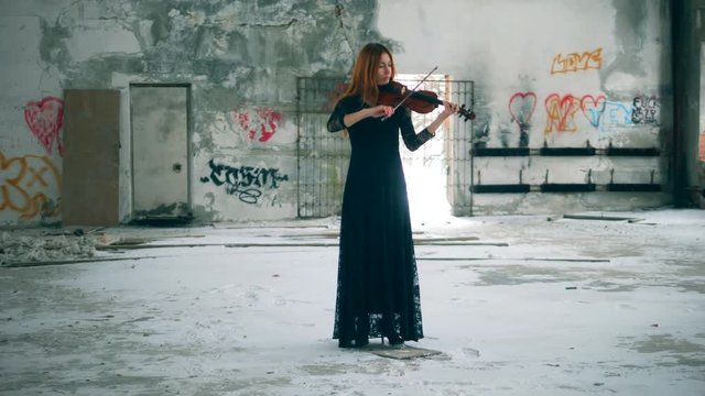 Abandoned building with a female violinist playing the instrument