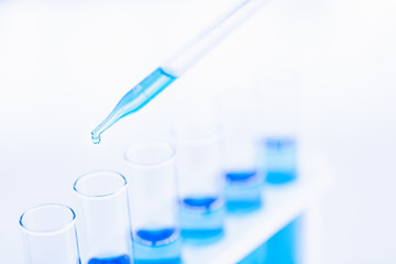 Someone dropping blue liquid in test tubes..
