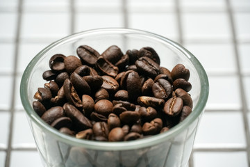 Isolated coffee beans in a glass bowl on white background.