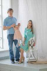 Fototapeta premium nice close-knit family of mom, dad and daughter posing in their white room