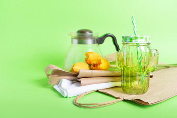 Zero waste living concept. Zero waste no plastic kit, Reusable Bag, Mason Jar, Microfiber Cloth, craft paper bag and yellow tulips on green background