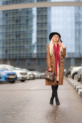 Beautiful young girl on the background of the wet streets of the spring modern city