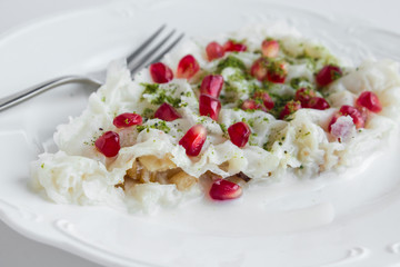 Traditional,Ramadan dessert Gullac one portion on the white porcelain plate.Crumbled walnut in and pistachio with pomegranate seeds for garnish.