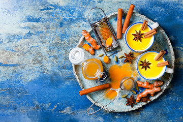 Turmeric golden milk latte with cinnamon sticks and honey. Detox, immune boosting, anti inflammatory healthy cozy drink