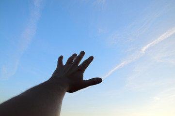 hand stretching to the blue clear sky