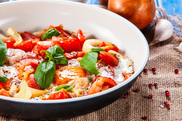 Shakshuka - fried eggs with vegetables in frying pan