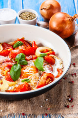 Shakshuka - fried eggs with vegetables in frying pan
