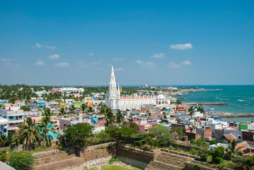 Our Lady of Ransom Shrine Church behind colorful houses on a sand beach occupied by fishing boats...