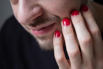 Man with red nail polish on his hands. Touching beard and face, smiling. Lifestyle photo. Lgbt community. Transsexual guy.