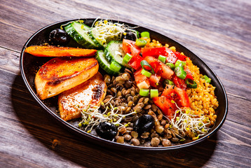 Groats with lentils and vegetables on wooden table