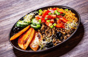 Groats with lentils and vegetables on wooden table