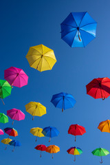 Fototapeta na wymiar Group of flying umbrellas isolated on blue background, ready for the rain, wallpaper background, bright various colors
