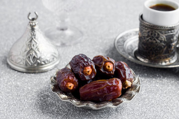 Traditional Arabian Bitter Coffee and dry date fruits on the shiny silver background.Ramadan...