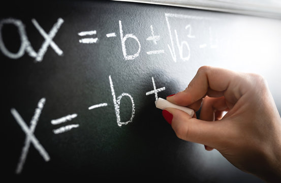 Math equation, function or calculation on chalkboard. Teacher writing on blackboard during lesson and lecture in school classroom. Student or tutor calculating or professor working.