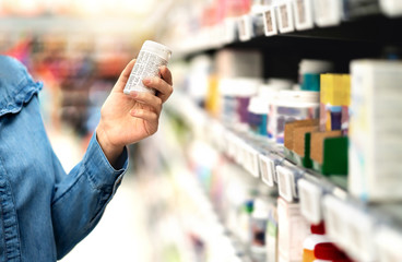 Kunde in der Apotheke mit Medizinflasche. Frau liest den Etikettentext über medizinische Informationen oder Nebenwirkungen in der Apotheke. Patienten-Einkaufspillen gegen Migräne oder Grippe. Vitamin- oder Zinktabletten.