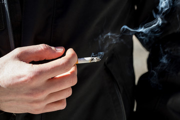 Closeup view of a cigarette in the hand of a Caucasian person