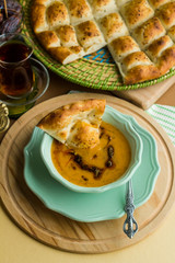 Traditional Turkish soup and Ramadan bread on the wooden plates.A triangle slice of Ramadan bread in soup.Ramadan concept.