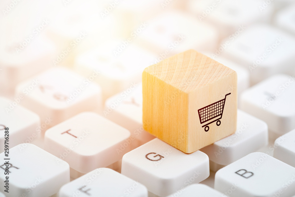 Poster wooden block with shopping cart graphic on computer keyboard. online shopping concept.