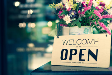 A business sign that says open on cafe or restaurant hang on door at entrance.