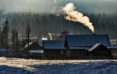Russian village in winter with fog and smoke from chimneys