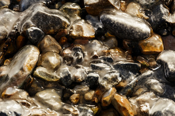 Pebbles at the shore covered with ice in winter