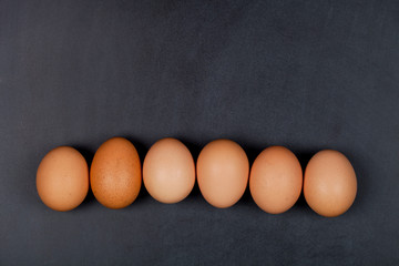 Six fresh organic chicken eggs on blackboard background.