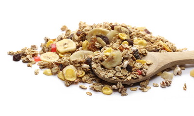Crunchy tropical muesli pile mix with banana, pineapple, papaya slices and raisins with wooden spoon isolated on white background
