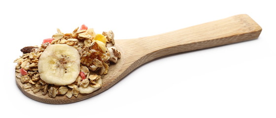 Crunchy tropical muesli pile mix with banana, pineapple, papaya slices and raisins with wooden spoon isolated on white background