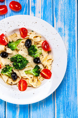 Pasta with herbs and vegetables on wooden background