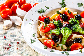 Pasta with herbs and vegetables on wooden background
