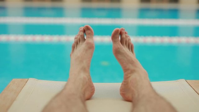 Male legs relaxing near swimming pool