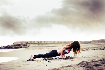 Young unrecognizable attractive brunette girl doping plank pilaes position at the beach on the...