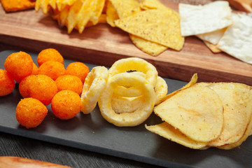Mix of snacks : pretzels , crackers , chips  and nachos on the table