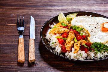 Grilled meat, white rice,fried egg vegetables on wooden table