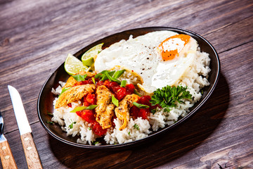 Grilled meat, white rice,fried egg vegetables on wooden table