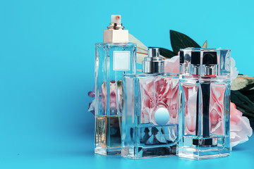 Perfume bottles with flowers on a light blue background
