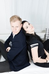 Young attractive business colleagues in love - sitting on bed back to back.
