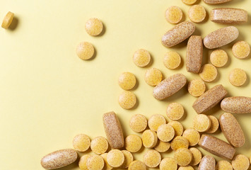 Top view of the heap of yellow medicine pills on yellow surface