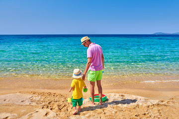 Fototapeta na wymiar Toddler boy on beach with father
