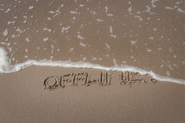 Fototapeta premium The word “offline” written in the sand symbolizing a time-out
