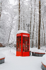 Red British telephone booth used as street library in winter (translated from Russian "Library")
