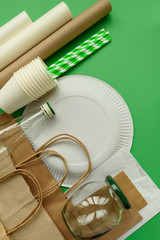 Paper and glass packages on green background. Copy space. Top view. Eco and save earth concept.