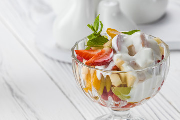 Bowl of healthy fresh fruit salad made of strawberry, apple and yoghurt