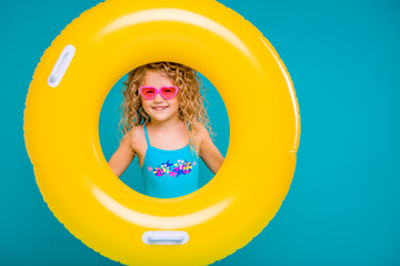 Cute girl in swimsuit holding swimming circle. Isolated on blue background .Summer holidays - pretty girl with inflatable ring 