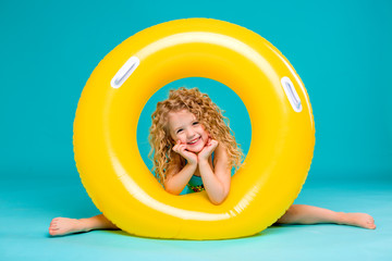 Cute girl in swimsuit holding swimming circle. Isolated on blue background .Summer holidays - pretty girl with inflatable ring 
