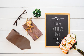 Happy Father's day concept. Flat lay image of gift box, necktie, glasses, rose flower and notebook with Happy Father's Day text.