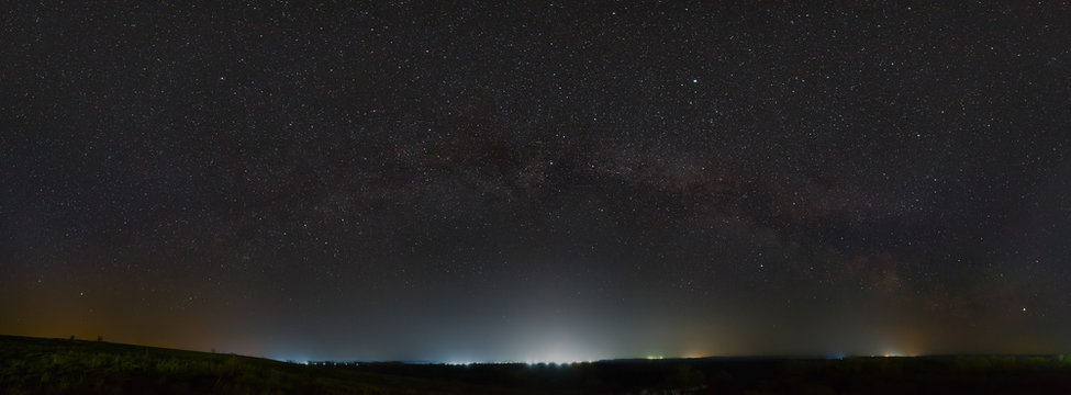 Stars Of The Milky Way In The Night Sky. Light Pollution From Street Lamps Above The Horizon.